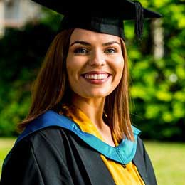 表演学生Celyn Cartwright在她的毕业礼服和帽子微笑。