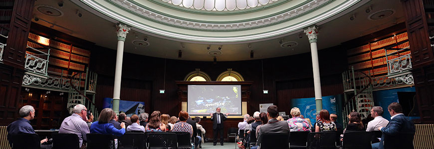 A man presents at a conference beneath the dome of Swansea College of Art's former library.