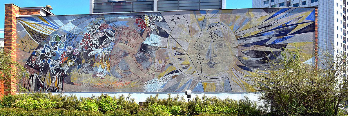墙上的马赛克展示了和平的象征:一只鸽子，一个年轻的女人和婴儿，一张被阳光包围的脸。