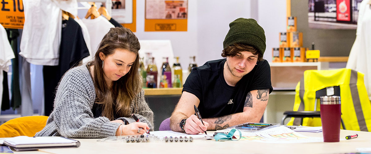 Two students writing in felt-tip at Swansea College of Art