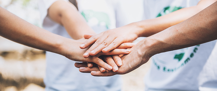 People stack their hands in a symbol of cooperation.