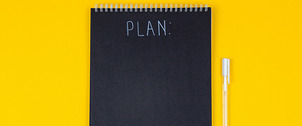 A black notebook with the single word PLAN written on it.