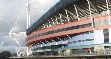 公国体育场的外部，下层包裹着彩色铝板，顶部可见钢屋顶支撑。