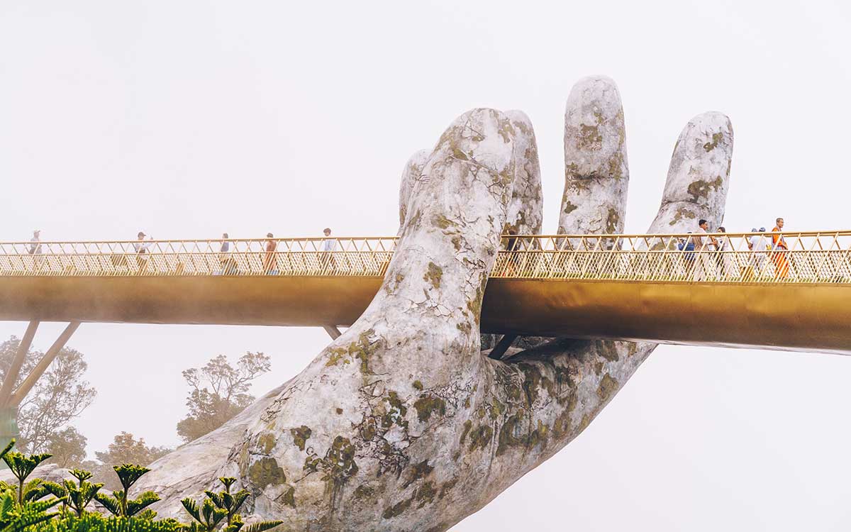 一座狭窄的金色人行天桥由一只巨大的石手支撑着。